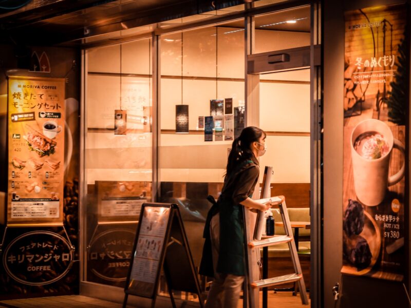 a woman standing outside of a coffee shop at night